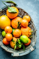 A basket filled with freshly picked oranges resting on natural wooden surface.