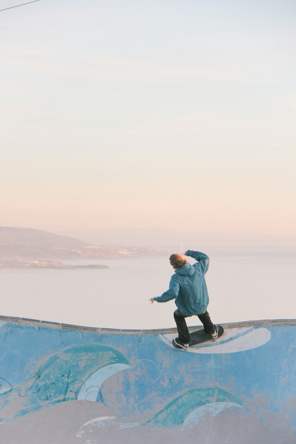 man in blue skateboarding on wall in beach