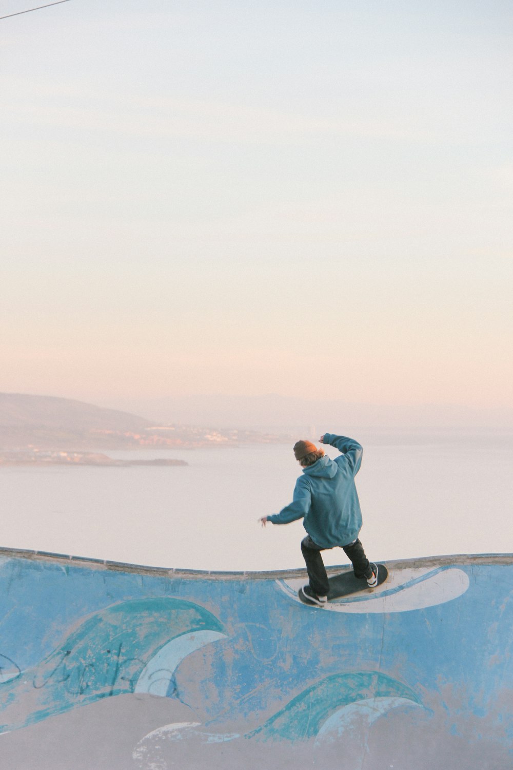 Uomo in skateboard blu sul muro in spiaggia