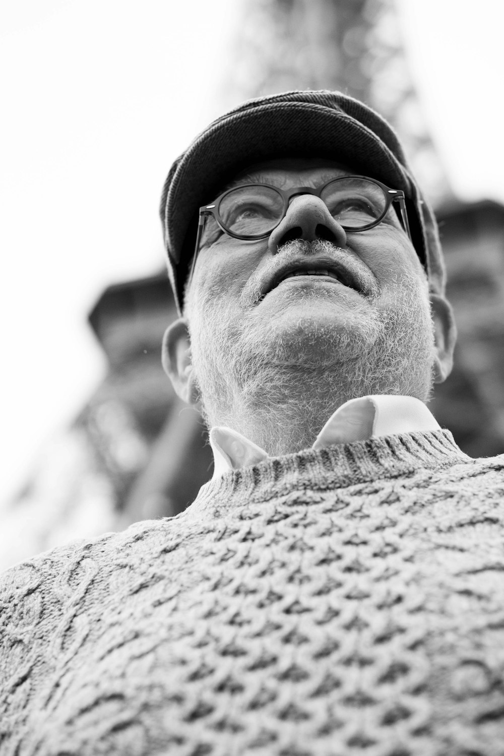 low angle view of man wearing hat and sweater under Eiffel Tower