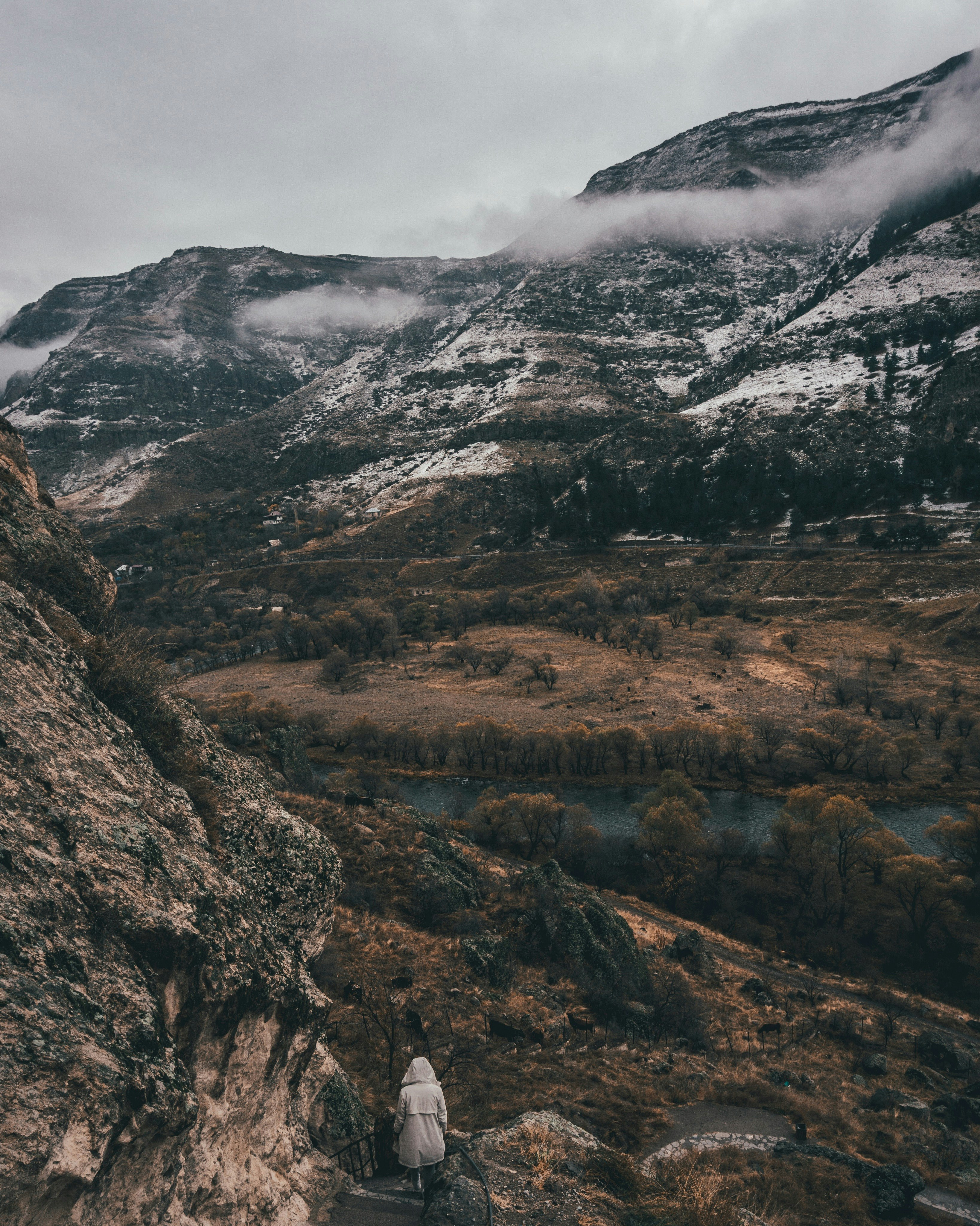 person walking down on stair beside mountain and river in nature photography