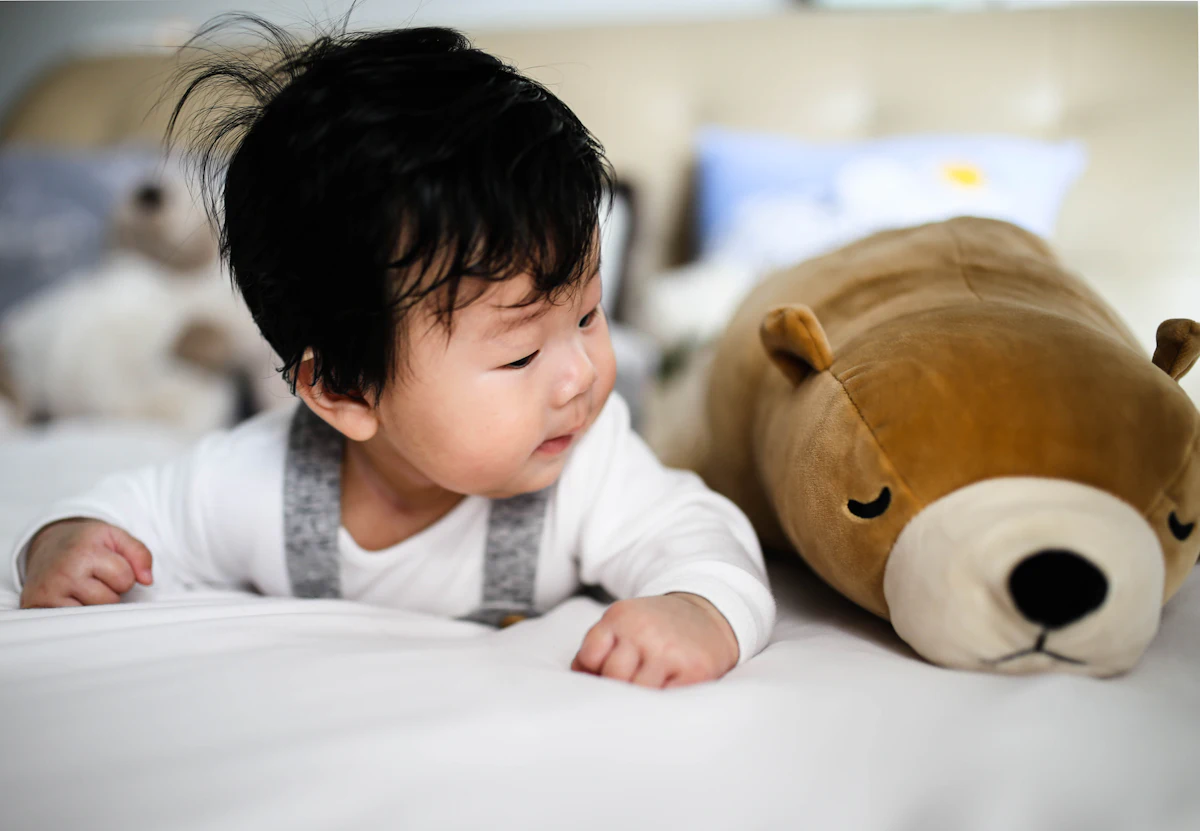 Bebé boca abajo jugando con un peluche