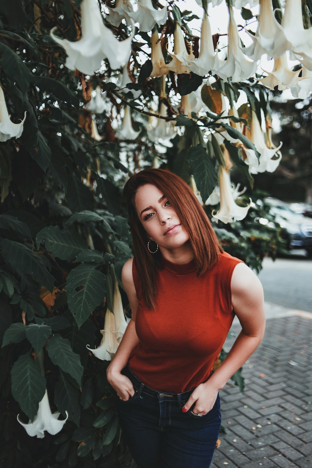 woman standing beside angels trumpet flower during daytime