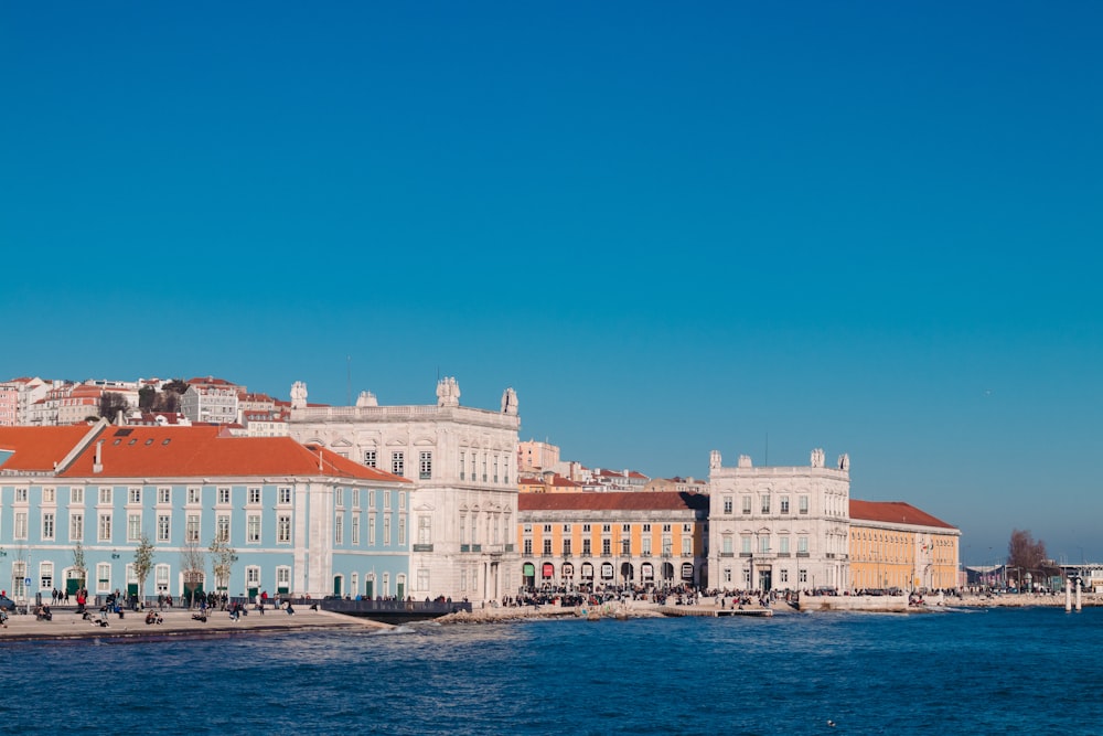 people by the beach beside buildings during daytime