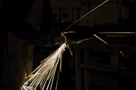 A professional craftsman using an angle grinder with sparks flying in a workshop.