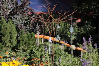 Bright garden scene with various colorful flowers and decorative stones arranged around green plants.