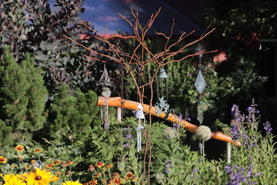 Bright garden scene with various colorful flowers and decorative stones arranged around green plants.