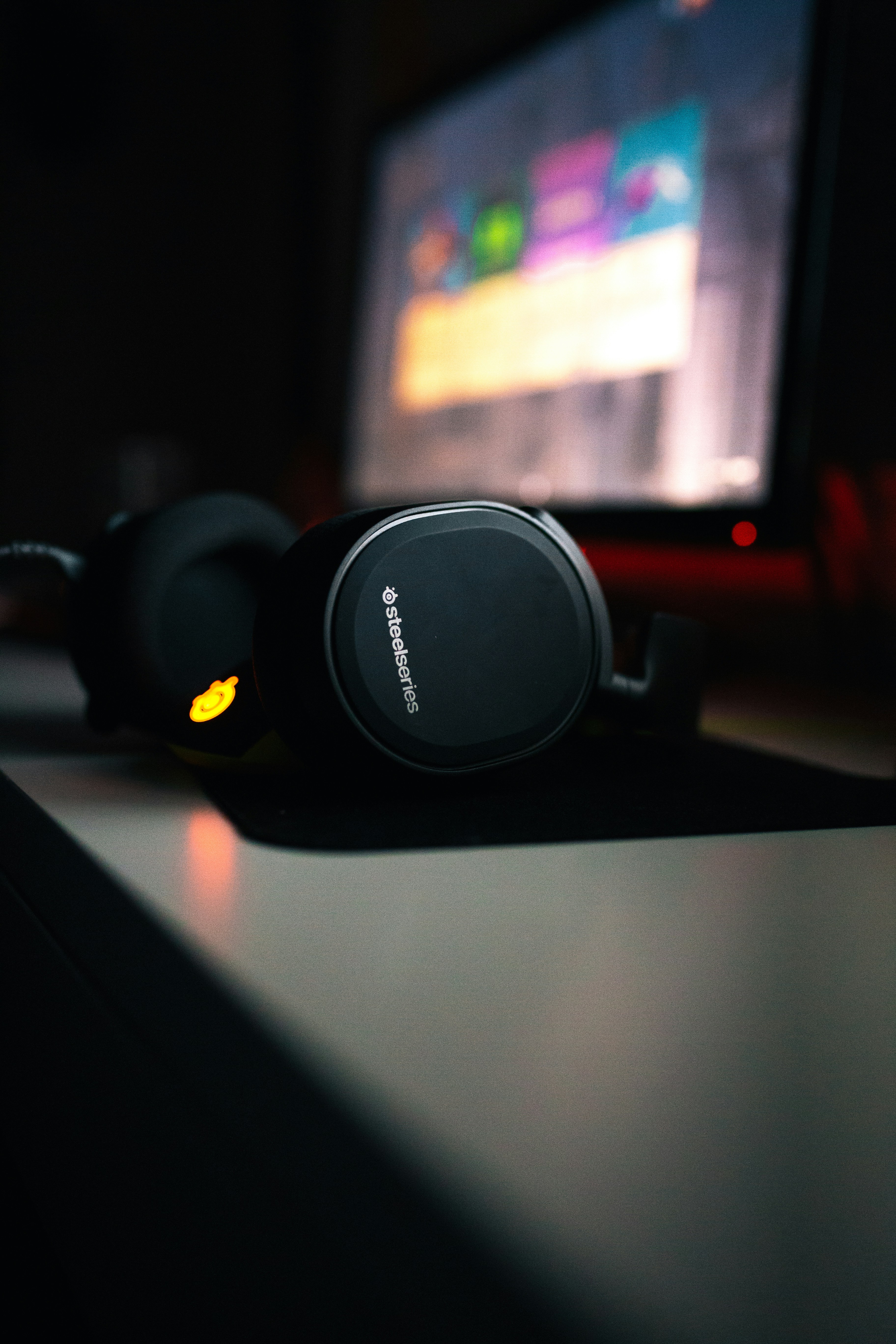 black headphones beside turned-on flat screen monitor