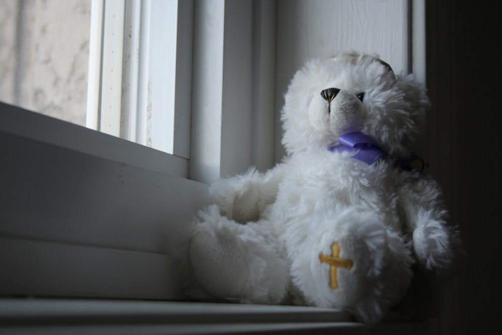 white teddy bear plush toy beside window