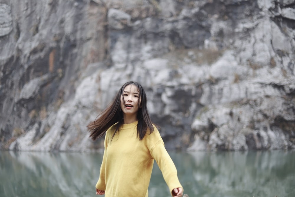 woman wearing yellow sweater near lake during daytime