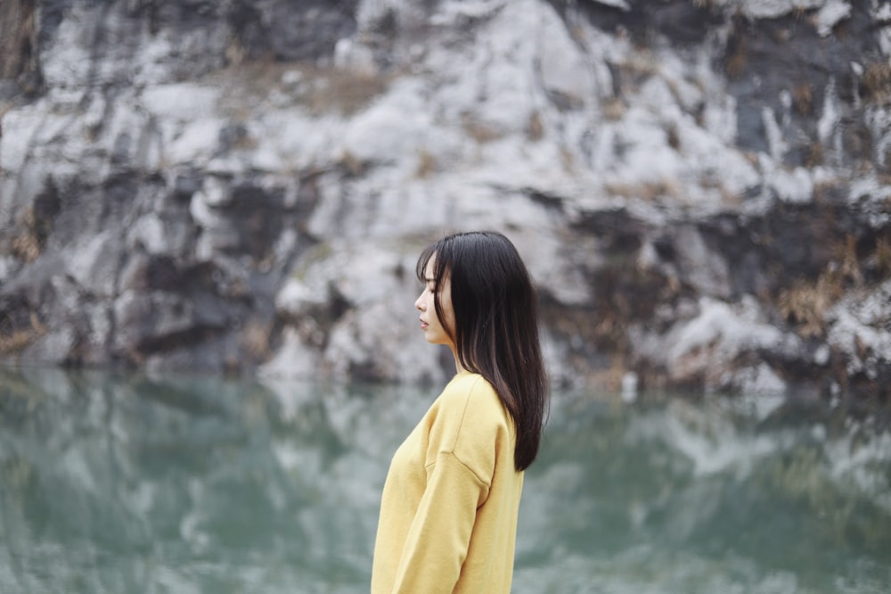 mujer de amarillo de pie junto al cuerpo de agua