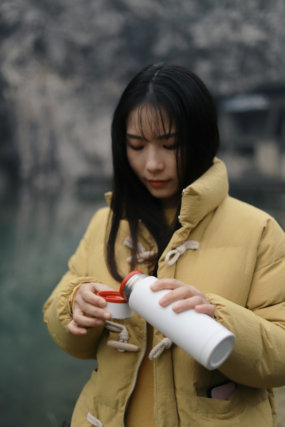woman holding vacuum flask putting water on lid