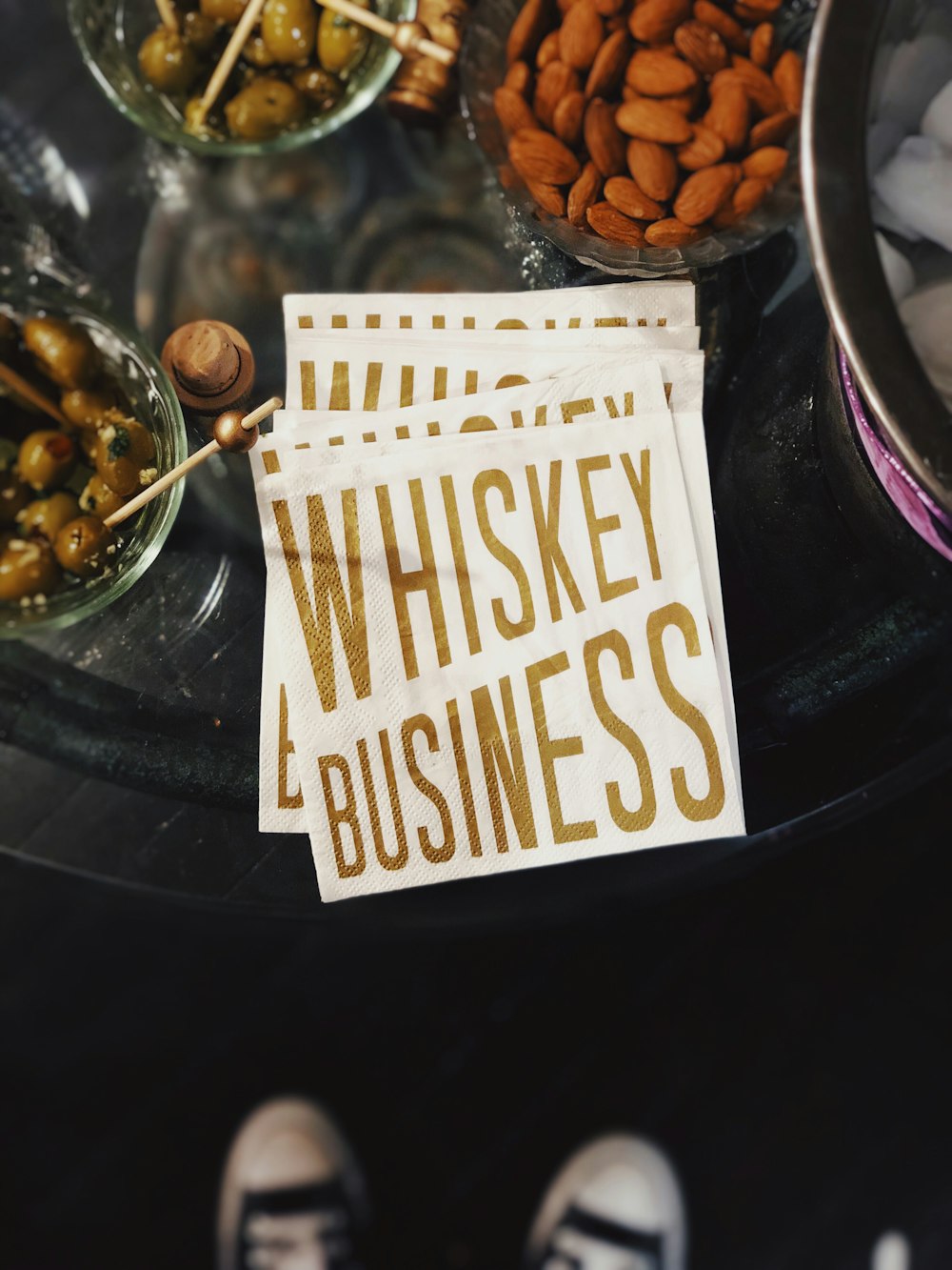 flat lay photo of almonds, green olives and whiskey signage