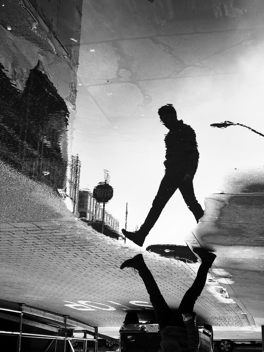 sombra de reflexión del agua del hombre que camina en la calle en la fotografía en escala de grises