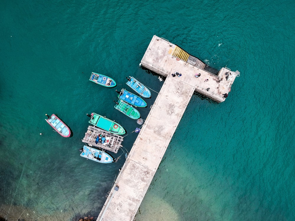 aerial photography of blue and green boats beside dock