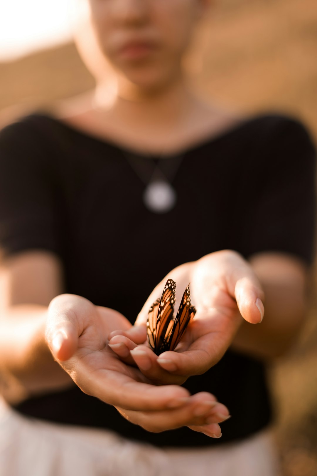 woman with monarch butterfly on her hand in close up photography