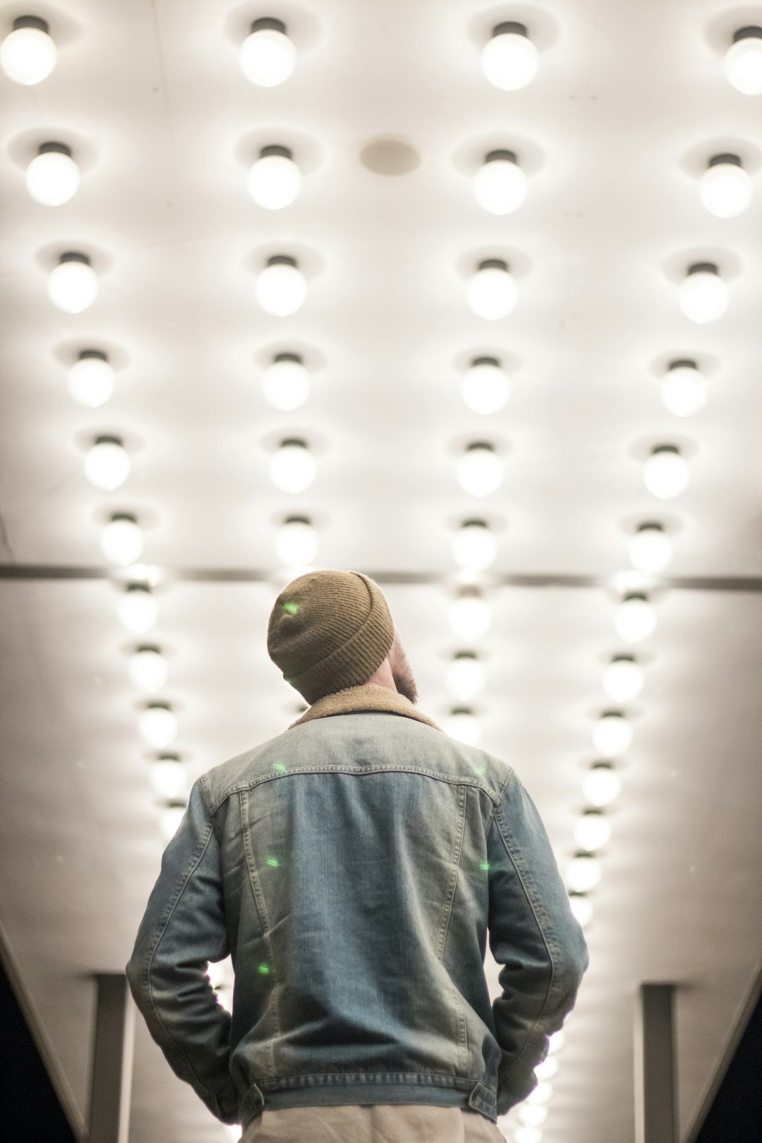 man in blue denim jacket standing on hall with lighted lights