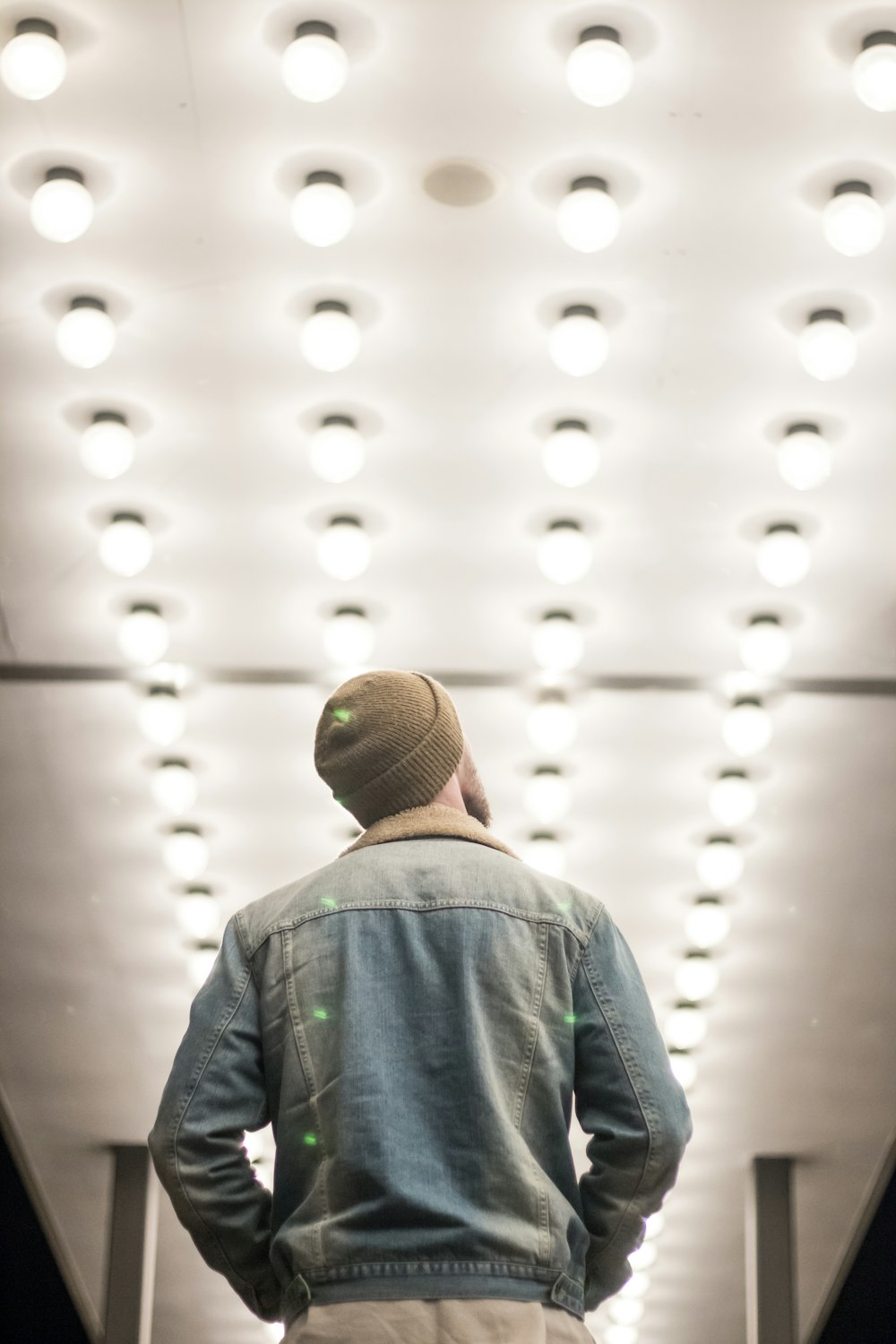 uomo in giacca di jeans blu in piedi sul corridoio con le luci illuminate