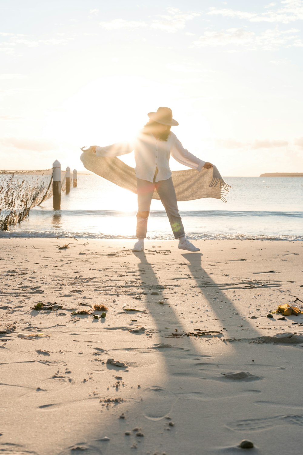hombre de pie en la orilla sosteniendo textil blanco frente al mar