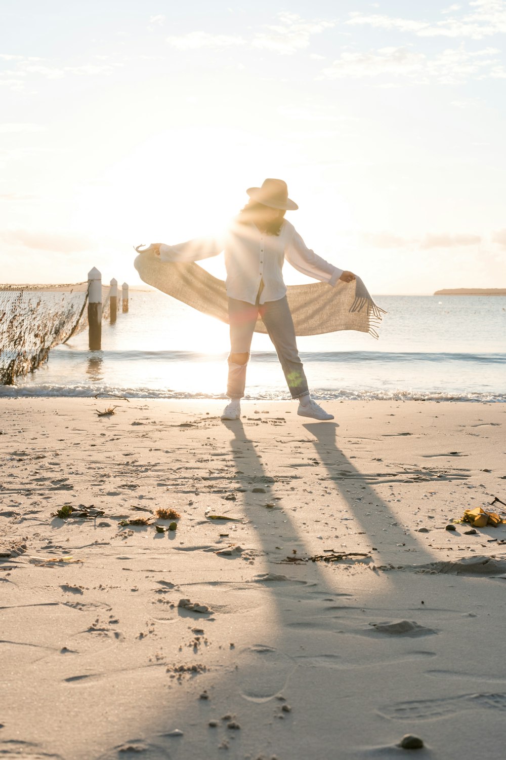 homme debout sur le rivage tenant le textile blanc devant la mer