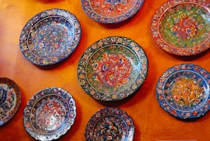 A display of painted ceramic plates featuring abstract designs in yellow and purple tones