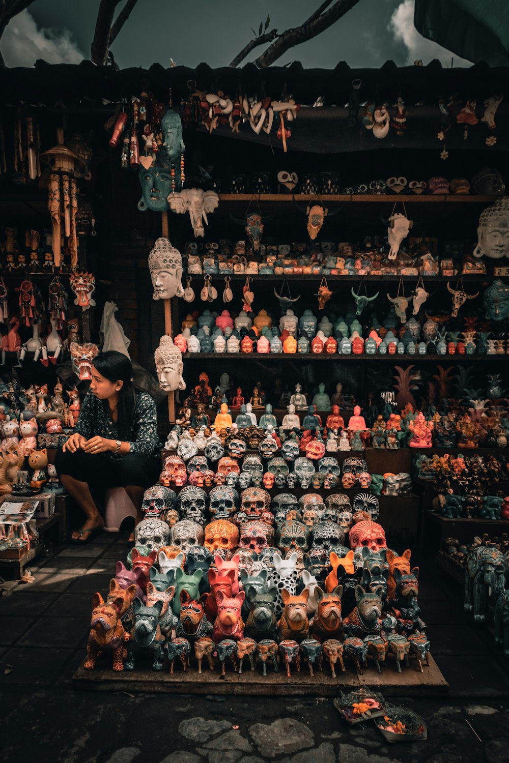 woman sits beside calavera figurine on display