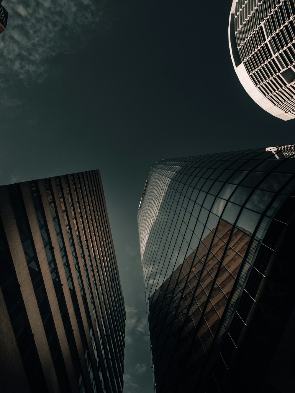 low angle photo of grey sky between 3 highrise buildings