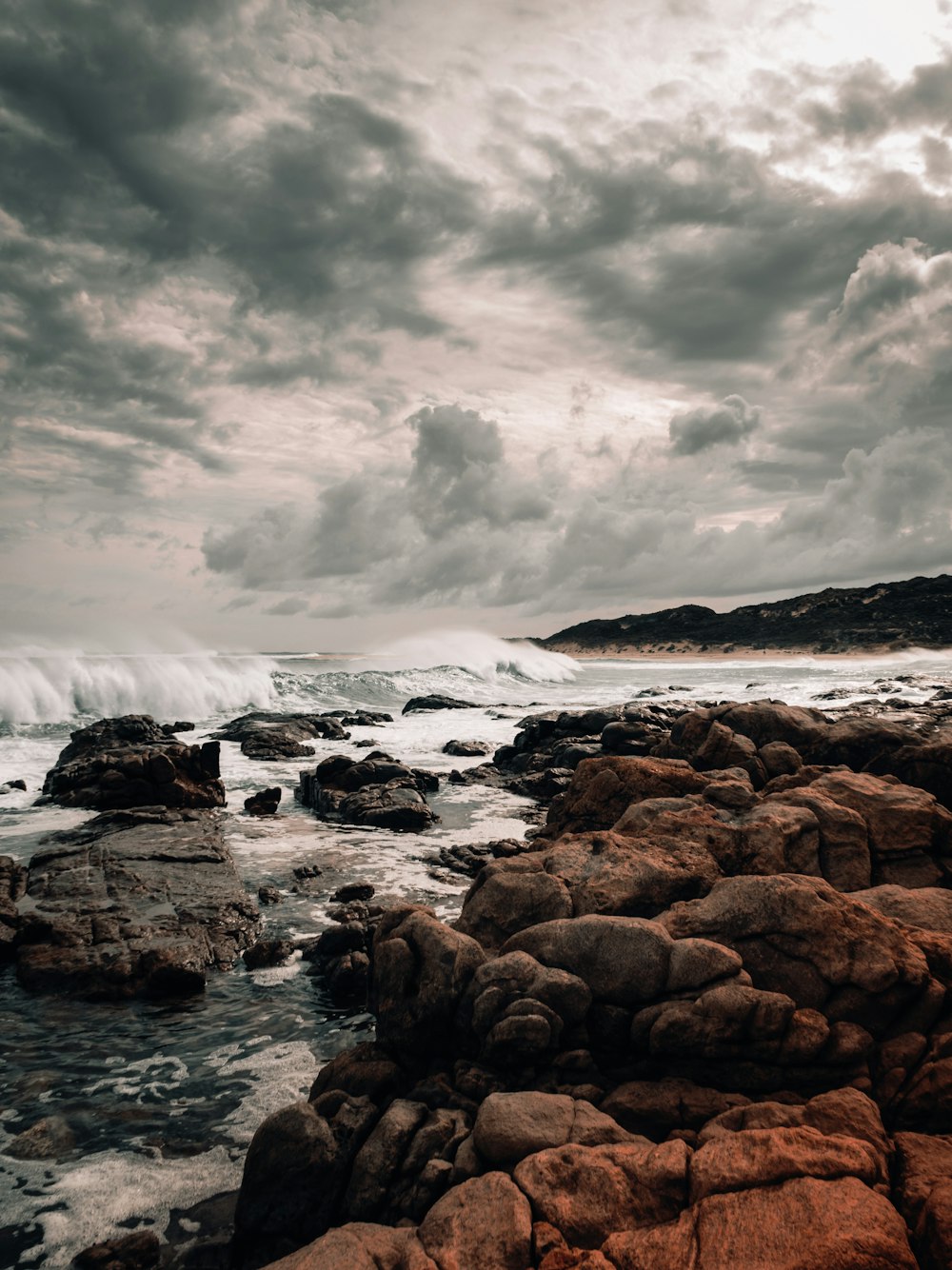 sea waves crashing on rocks under dramatic clouds