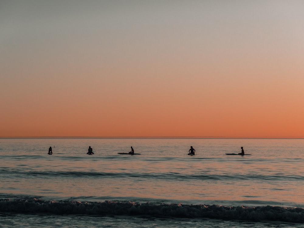 five people surfing on sea