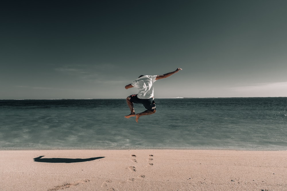 man suspended in air above beach sand