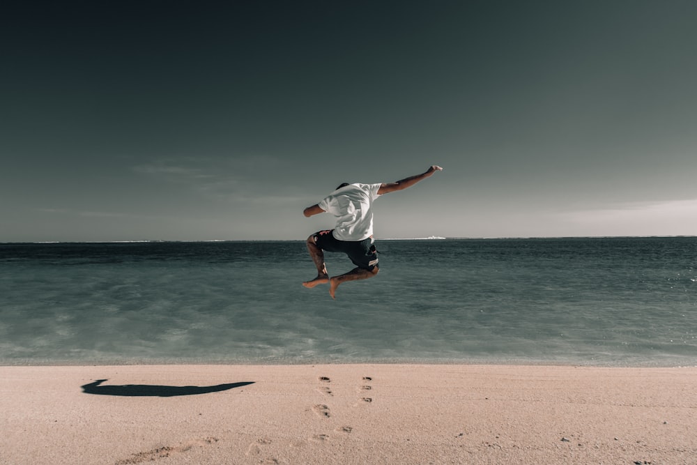 hombre suspendido en el aire sobre la arena de la playa