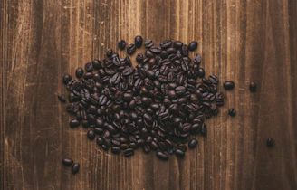 Golden roasted robusta coffee beans piled on a dark wooden surface.