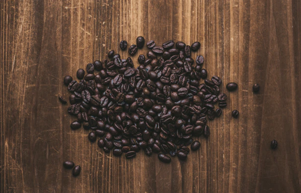 Golden roasted robusta coffee beans piled on a dark wooden surface.