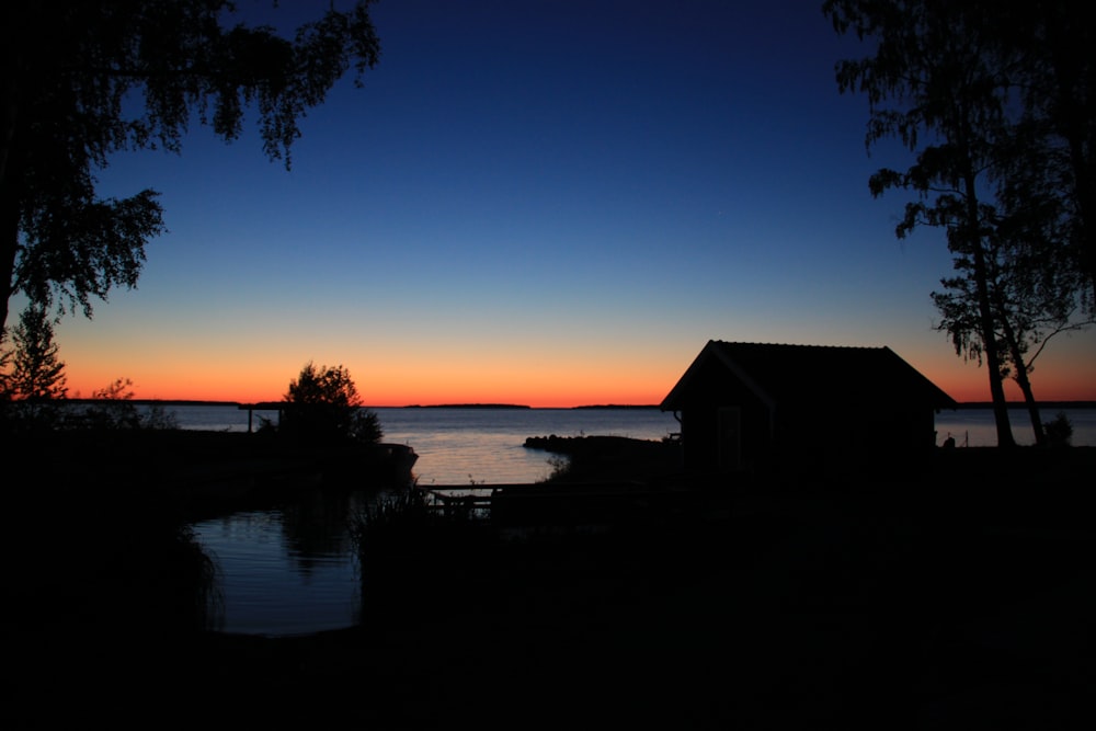 silhouette of house beside body of water