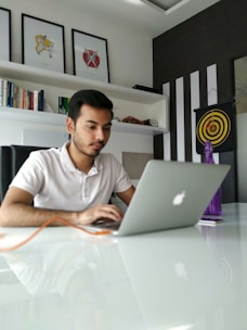 A focused entrepreneur working on a laptop with sales charts and CRM software on screen in a minimalist black and white office.