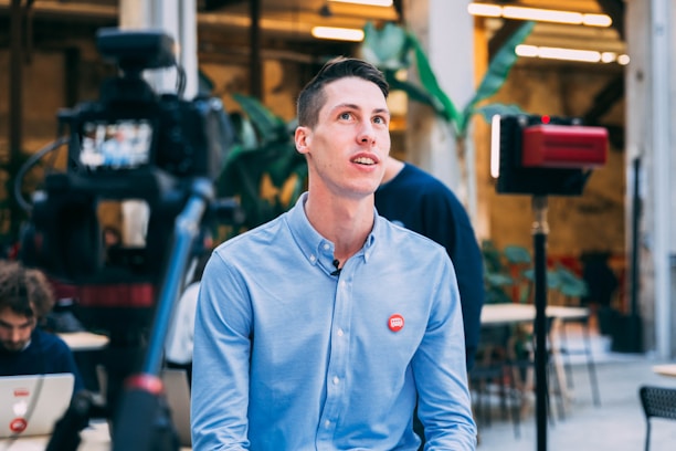 A friendly marketer speaking directly to the camera in a modern tech office.