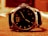 Close-up of a luxury wristwatch resting on a wooden surface with soft natural lighting.