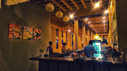 Evening scene at The Coffee Stop with glowing pendant lights and cocktails on the bar.