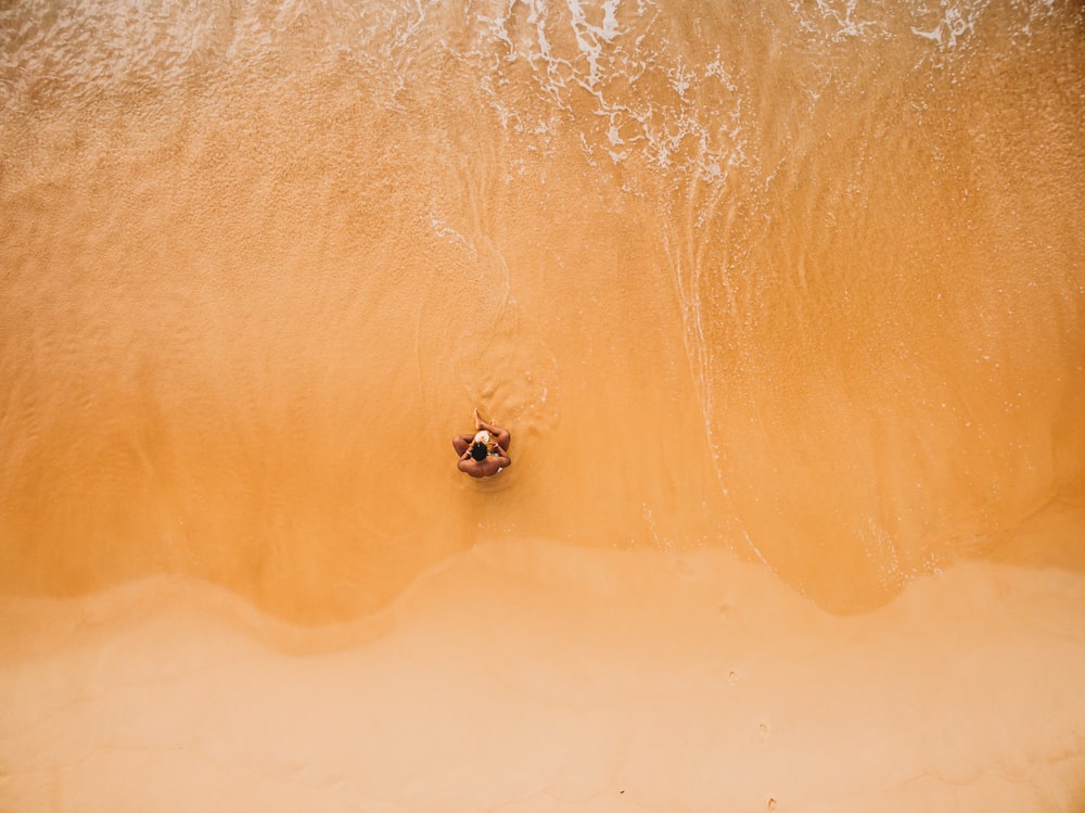 Luftaufnahme eines Mannes, der am Meeresufer sitzt