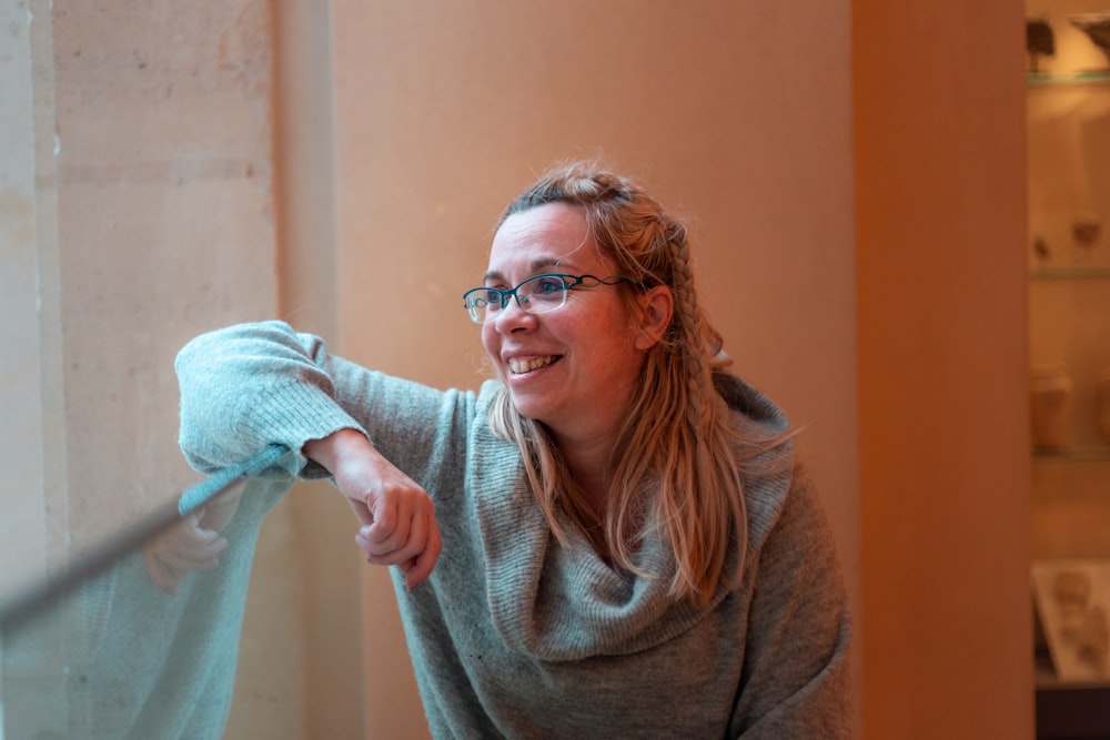 smiling woman leaning on glass board in room