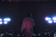 Speaker standing confidently on stage, spotlight highlighting their presence.