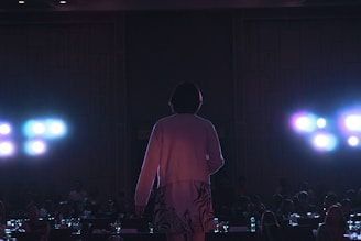 An individual standing confidently on a stage, sharing their story with an attentive audience.