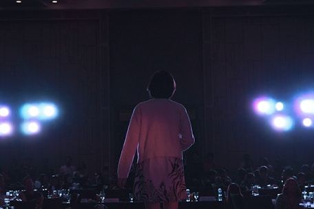An individual standing confidently on a stage, sharing their story with an attentive audience.