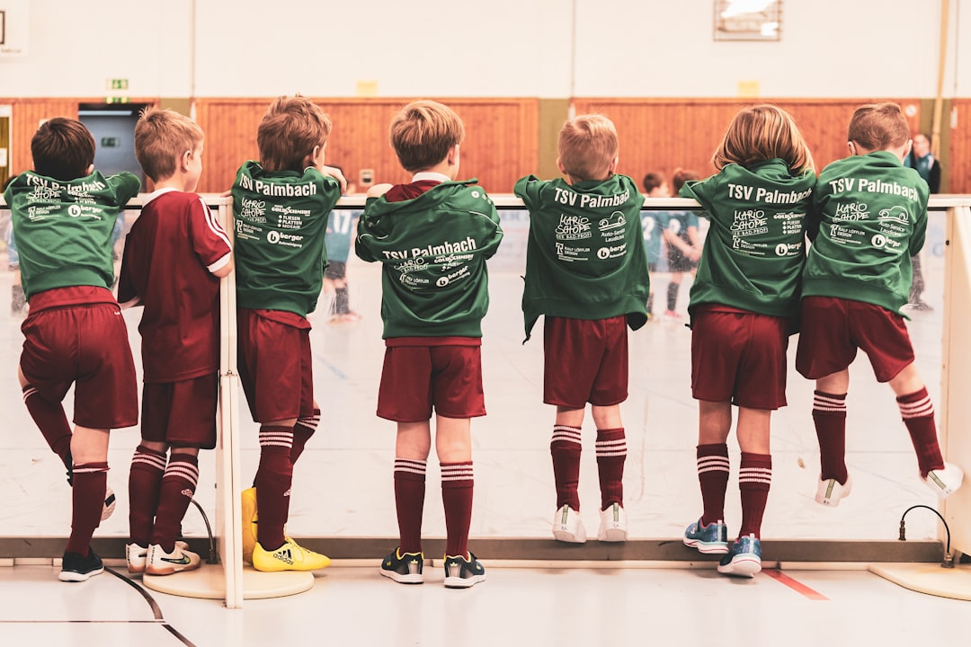 toddlers wearing sports jersey suit standing near white wall