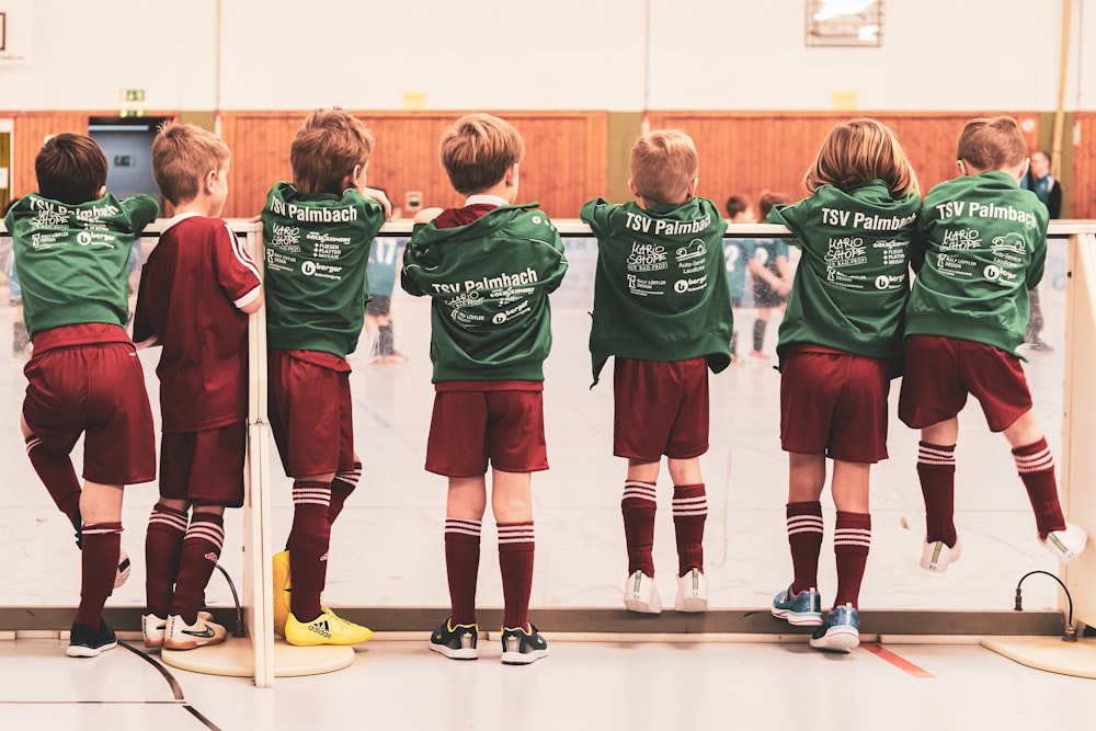 niños pequeños con traje de jersey deportivo de pie cerca de la pared blanca