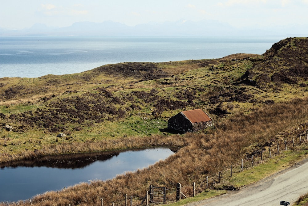 brown house near body of water and hills during daytime