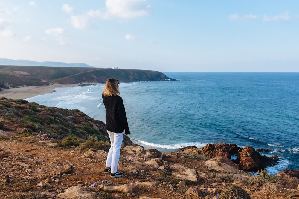 woman standing and facing body of water during daytime