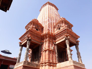 Rows of intricately carved temple pillars standing tall against a clear sky.