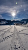 A close-up of tire tracks on a frozen surface leading into the horizon.