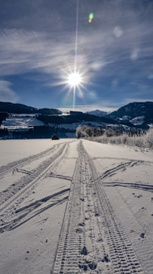 A close-up of tire tracks on a frozen surface leading into the horizon.